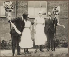 Two men holding tutti poles, with two women during the Hocktide Festival in Hungerford, 1925-35. Creator: George R Long
