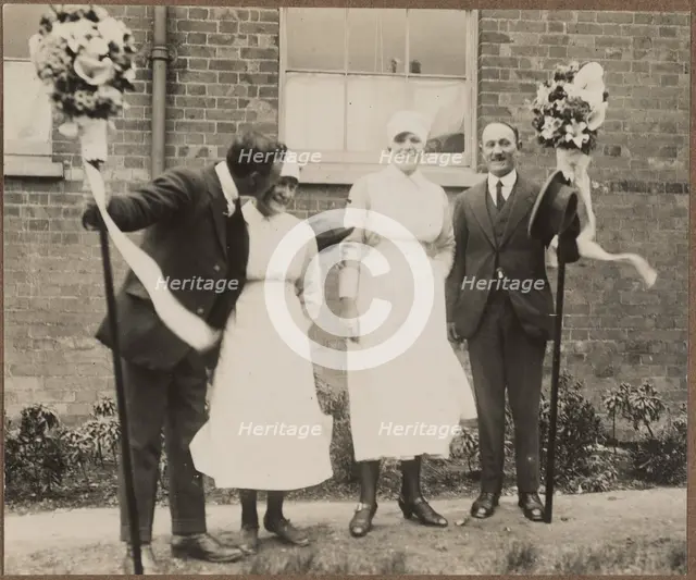Two men holding tutti poles, with two women during the Hocktide Festival in Hungerford, 1925-35.  Creator: George R Long.
