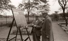 Two men in flat caps look at the bowls scoreboard, York, Yorkshire, 1955