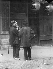 Two men, one holding a child, standing in the street, Chinatown, San Francisco, c1896-1906. Creator: Arnold Genthe