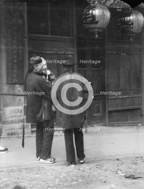 Two men, one holding a child, standing in the street, Chinatown, San Francisco, c1896-1906. Creator: Arnold Genthe.