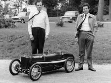 Two men standing by a miniature Sunbeam pedal car, 1960s