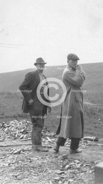 Two men standing near a small pile of rubble, in a field, between c1900 and 1916. Creator: Unknown.