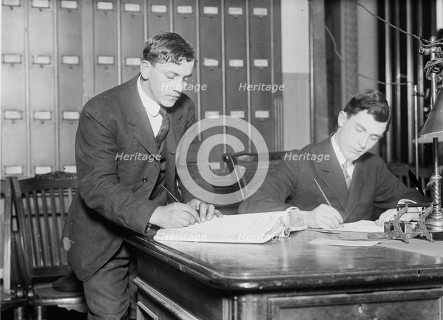 Two new citizens sign naturalizaton papers in judge's chambers, 1910. Creator: Bain News Service.