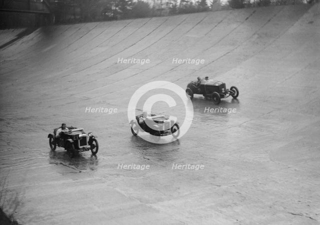 Two Austin 7s and an unidentified car racing at a BARC meeting, Brooklands, Surrey, 1931 Artist: Bill Brunell.