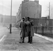 Two Afro-Caribbean men reading a map in the street, London, (c1950s?). Creator: Henry Grant