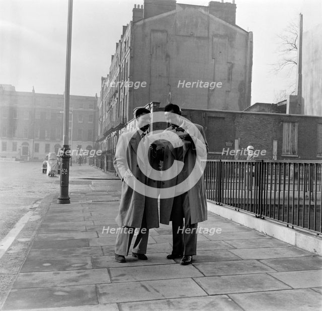 Two Afro-Caribbean men reading a map in the street, London, (c1950s?).   Creator: Henry Grant.