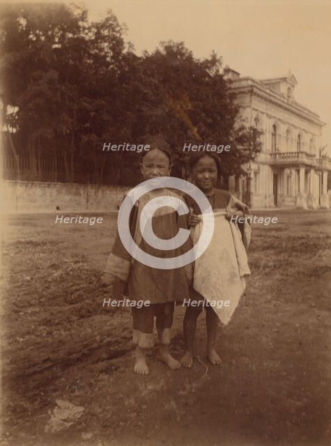 Two barefoot children standing in muddy street in front of the Lindholm's large..., (1899?). Creator: Eleanor Lord Pray.