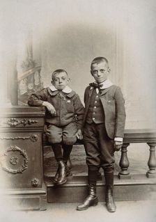 Two boys, one sitting and one standing: the former appears physically deformed, 1899. Creator: Unknown
