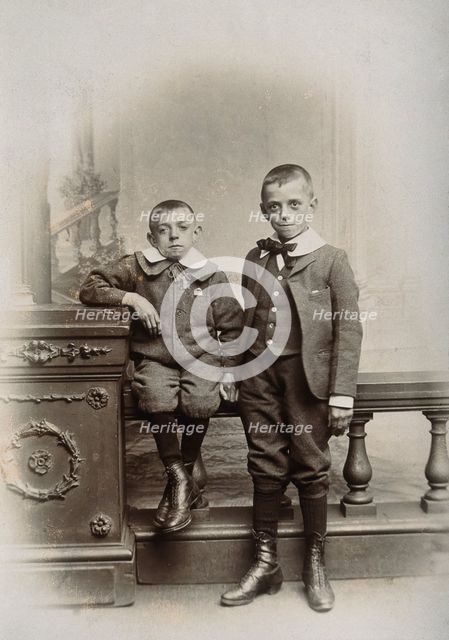 Two boys, one sitting and one standing: the former appears physically deformed, 1899. Creator: Unknown.