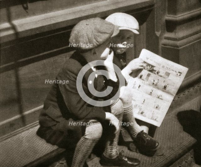 Two boys reading the comic section of the Sunday paper, New York, USA, 1931. Creator: Unknown.