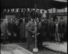 Two British Men Guiding a Time Capsule Being Lowered in the Ground With Various Civilians..., 1938. Creator: British Pathe Ltd