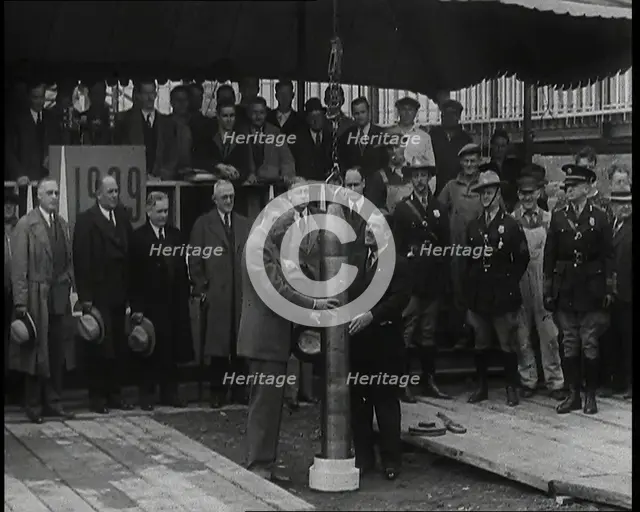 Two British Men Guiding a Time Capsule Being Lowered in the Ground With Various Civilians..., 1938. Creator: British Pathe Ltd.