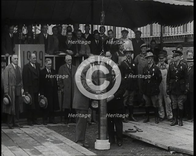 Two British Men Guiding a Time Capsule Being Lowered in the Ground With Various Civilians..., 1938. Creator: British Pathe Ltd.