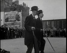 Two British Men in Suits and Hats Dancing in a Square With Men and Woman Watching Them..., 1938. Creator: British Pathe Ltd