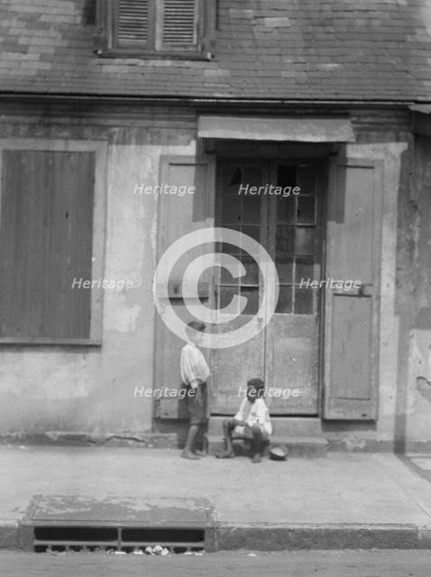 Two children outside a door with shutters in the French Quarter, New Orleans, between 1920 and 1926. Creator: Arnold Genthe.