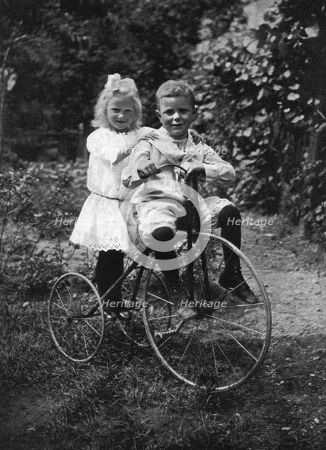 Two children on a tricycle, 1911-1912.Artist: CW Perry