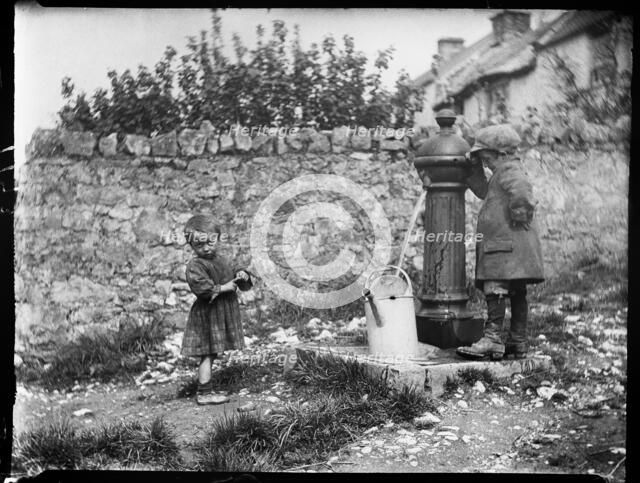 Two children collecting water at a water pump, Cheddar, Somerset, 1907. Creator: Katherine J Macfee.