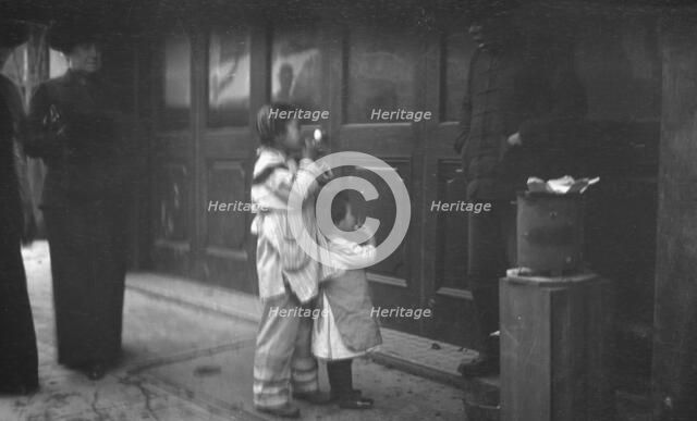 Two children standing on a sidewalk eating, Chinatown, San Francisco, between 1896 and 1906. Creator: Arnold Genthe.