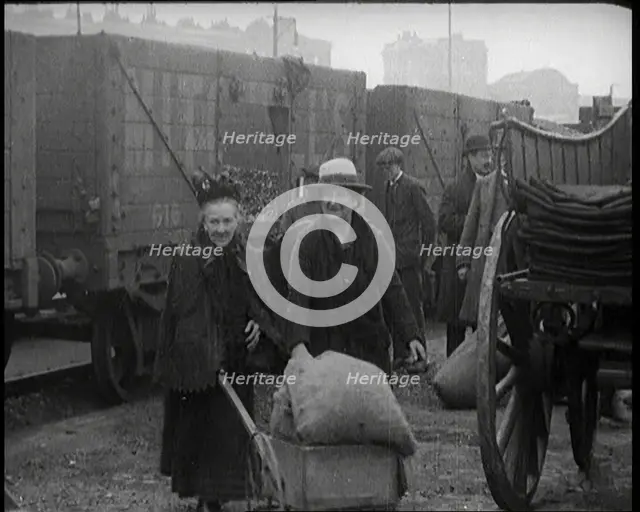 Two Elderly Female Civilians Wheeling a Barrow of Coal Away from a Railway Truck As Other..., 1924. Creator: British Pathe Ltd.