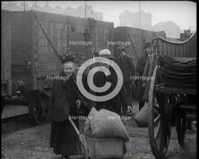 Two Elderly Female Civilians Wheeling a Barrow of Coal Away from a Railway Truck As Other..., 1924. Creator: British Pathe Ltd.