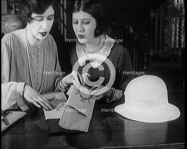 Two Female Civilians Cutting  Sheets of Paper to Decorate a Hat, 1920. Creator: British Pathe Ltd.