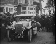 Two Female Civilians Explorers Driving Away in Their Heavily Loaded Car Watched by a Small..., 1920. Creator: British Pathe Ltd