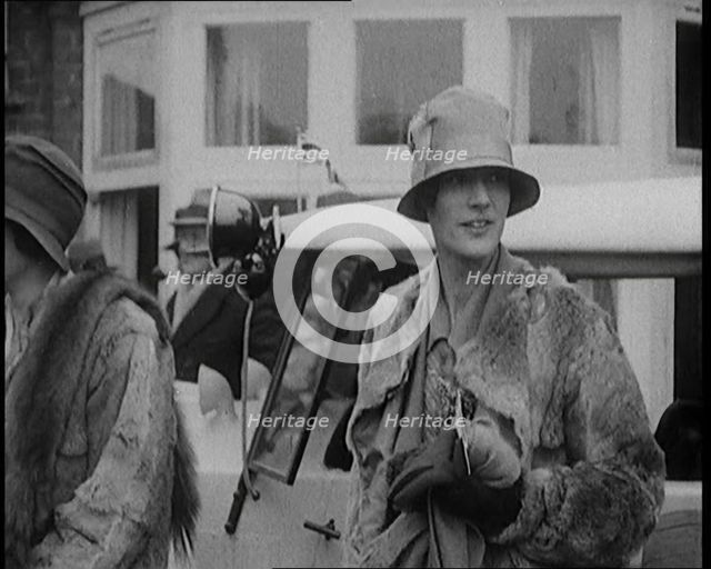 Two Female Civilians Wearing Heavy Coats and Hats Standing in Front of a Car, 1920. Creator: British Pathe Ltd.
