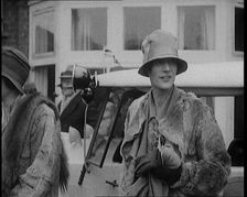 Two Female Civilians Wearing Heavy Coats and Hats Standing in Front of a Car, 1920. Creator: British Pathe Ltd