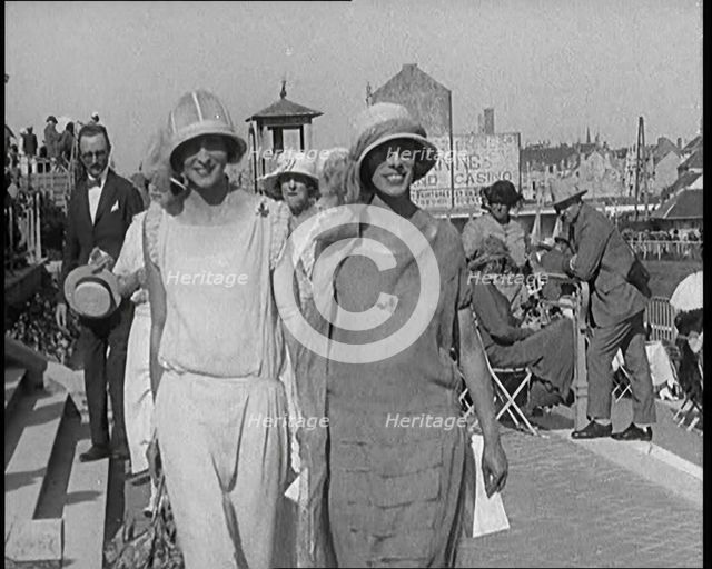 Two Female Civilians Wearing Smart Outfits Walking Towards the Camera in a Horse Race Event, 1920. Creator: British Pathe Ltd.