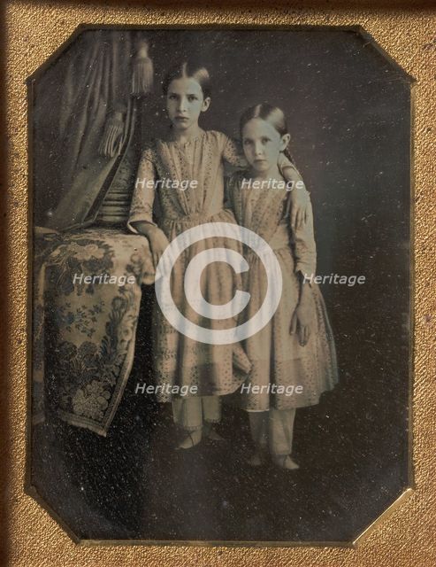 Two Identically Dressed Young Girls Standing Next to a Table, 1840s. Creator: Unknown.
