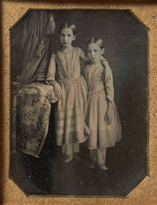 Two Identically Dressed Young Girls Standing Next to a Table, 1840s. Creator: Unknown