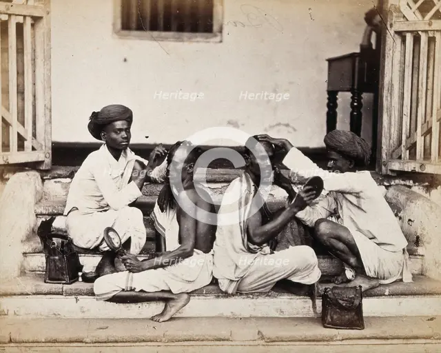 Two Indian barbers wearing turbans shaving the heads of two Indian men..., c1900s. Creator: Unknown.