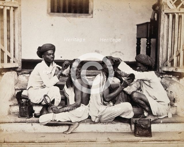Two Indian barbers wearing turbans shaving the heads of two Indian men..., c1900s. Creator: Unknown.
