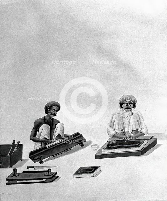 Two Indian bookbinders: one trimming page edges in a press, the other decorating a binding. Creator: Unknown.