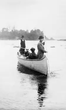 Two Indian guides(?) standing, and two women seated...Sault Sainte Marie region of Michigan, 1903. Creator: Frances Benjamin Johnston
