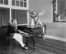 Two Pierrot clowns performing a routine with a piano, 1917. Artist: Bedford Lemere and Company