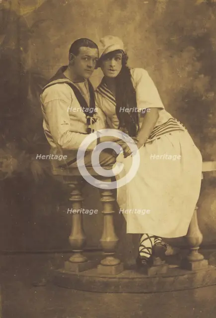 Two sailors, one in drag, embracing while sitting on a stage balcony, (between 1910 and 1919?). Creator: Unknown.