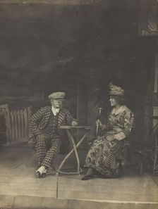 Two sailors, one in drag, sit on stage at a table, in front of very detailed scenery (1910-1919?). Creator: Unknown