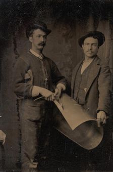 Two Tinsmiths Cutting a Curled Sheet of Metal, 1880s. Creator: Unknown