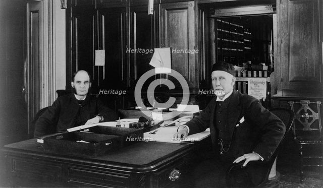 Two Treasury Department employees seated at desk in office, between 1884 and 1930. Creator: Frances Benjamin Johnston.