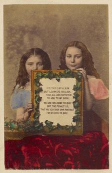 Two unidentified girls holding a framed picture with text, 1870-1875. Creator: Burgwitz & Company