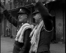 Two Uniformed British Soldiers With Arms Raised Standing Outside Brick Building, 1937. Creator: British Pathe Ltd
