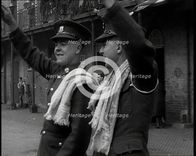 Two Uniformed British Soldiers With Arms Raised Standing Outside Brick Building, 1937. Creator: British Pathe Ltd.