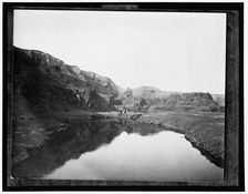 Two women by water, rocky cliffs in background, between 1900 and 1906. Creator: Unknown