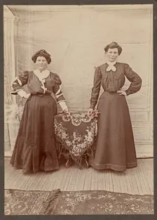 Two women standing at a table holding flowers, about 1875. Creator: Unknown