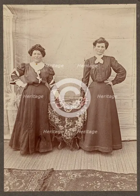 Two women standing at a table holding flowers, about 1875. Creator: Unknown.