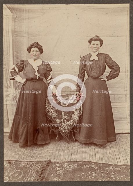 Two women standing at a table holding flowers, about 1875. Creator: Unknown.
