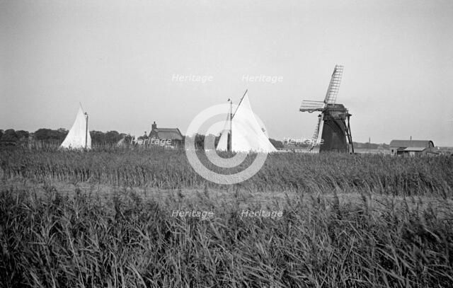 Two yachts under sail seen over the reed beds near East Tunstall Mill, Norfolk, 1934.  Artist: HES Simmons