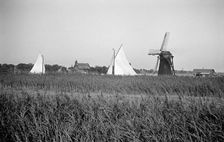 Two yachts under sail seen over the reed beds near East Tunstall Mill, Norfolk, 1934. Artist: HES Simmons